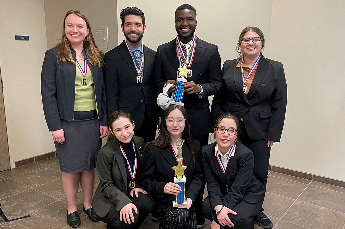 group of students in black suits holding trophies and awards